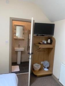 a bathroom with a television and a sink in a room at Palmer's Ale House in Long Sutton