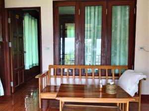 a wooden bench sitting in a room with windows at Three Monkeys Bungalows Koh Yao Noi in Ko Yao Noi