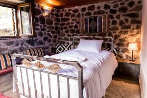 1 dormitorio con 1 cama en una pared de piedra en Πέτρινη κατοικία με υπέροχη θέα στο όρος Κόζιακα. 
