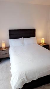 a bedroom with a large white bed with two lamps at Stunning 1 Bedroom Apartment in London