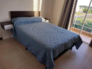 1 dormitorio con 1 cama con edredón azul y ventana en Residencia Merlo en Rafaela