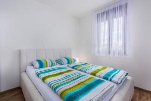 a white bedroom with a bed with colorful blankets and pillows at Mandy & Mia in Novigrad Istria