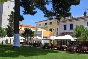 a building with tables and umbrellas in a park at Apartment Ida in Novigrad Istria