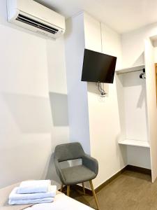 a room with a chair and a tv on a wall at Apartamentos Fuencarral in Madrid