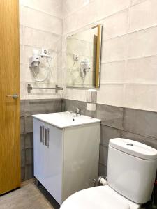 a bathroom with a toilet and a sink and a mirror at Apartamentos Fuencarral in Madrid