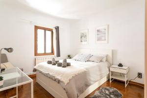 a white bedroom with a bed and a window at Barcelona Beach Home in Barcelona