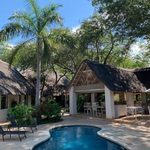 a resort with a swimming pool in front of a house at Pamarah Lodge in Victoria Falls