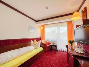 バート・ヴェーリスホーフェンにあるKurhotel Wiedenmannのベッド1台、薄型テレビが備わるホテルルームです。