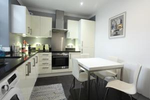 a kitchen with white cabinets and a white table and chairs at Walk to Notting Hill /Paddington 1 B/R with patio in London