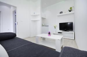 a white living room with a couch and a tv at Apartment Borovac in Vrgorac