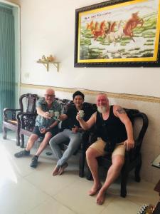 un grupo de tres hombres sentados en un banco en Huy Hoàng Motel - Cần Thơ en Can Tho