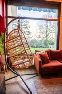 eine Rattanschaukel im Wohnzimmer mit Sofa in der Unterkunft Villa avec vue panoramique in Charleville-Mézières