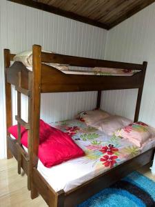 a wooden bunk bed with pink pillows on it at Chalet de Bérènice in Saint-Joseph