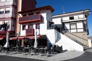 a restaurant with chairs and umbrellas in front of a building at PORTU ZARRA Bermeo in Bermeo