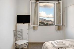 a bedroom with a bed and a window and a chair at Funchal House in Funchal