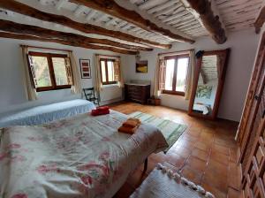 Schlafzimmer mit einem Bett, einem Tisch und Fenstern in der Unterkunft Casa de Alguaztar in Bubión