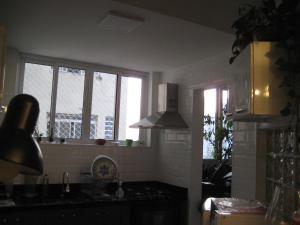 een keuken met 2 ramen, een wastafel en een fornuis bij QUARTO COM BANHEIRO PRIVATIVO in Sao Paulo