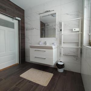 ein weißes Badezimmer mit einem Waschbecken und einem Spiegel in der Unterkunft Domek u Litwinów in Lipowiec