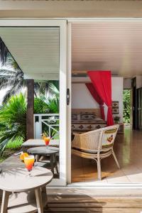 una puerta abierta a un patio con mesa y sillas en Hotel Coucoue Lodge en Assinie
