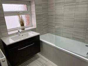 a bathroom with a sink and a bath tub and a window at Apex Living NE - Carnegie House 4 Bed House, FREE PARKING FREE WiFi 