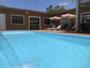 uma grande piscina azul em frente a uma casa em Hotel Tito's em Capanema