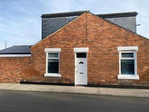 a brick building with a white door and two windows at Apex Living NE - Carnegie House 4 Bed House, FREE PARKING FREE WiFi in Ryhope