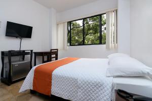 a bedroom with a bed and a flat screen tv at Hotel de Alborada in Guayaquil