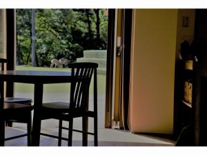 a dining room table with two chairs and a cat out the window at Mountain Home Lodge in Deer Park in Nara