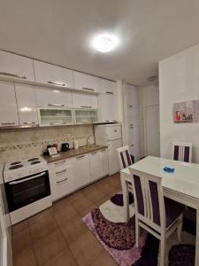 a kitchen with white cabinets and a table with chairs at Your place in Podgorica in Podgorica