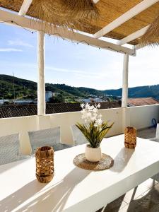 einen weißen Tisch mit Stühlen und Blumen auf dem Balkon in der Unterkunft 4Cantos Alentejo in Mértola