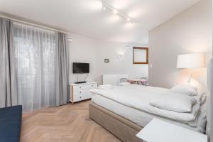 a white bedroom with a large bed and a television at Apartament Solidarności by Your Freedom in Warsaw