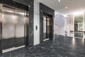 korytarz z podłogą wyłożoną czarnym marmurem i drzwiami windy w obiekcie Apartament Solidarności by Your Freedom w Warszawie