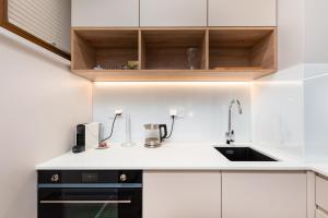 a kitchen with white cabinets and a sink at Apartament Solidarności by Your Freedom in Warsaw
