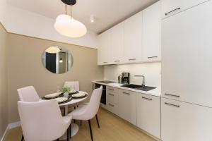 - une cuisine avec des placards blancs, une table et des chaises dans l'établissement Apartamenty Polanki Aqua - visitopl, à Kołobrzeg