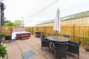 a patio with a bed and a table and chairs at The Old Byre with Hot Tub in Forgandenny