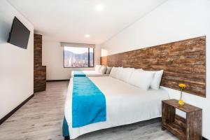 um quarto com uma grande cama branca e uma parede de madeira em HOTEL AMERICAN VISA CORPORATE em Bogotá