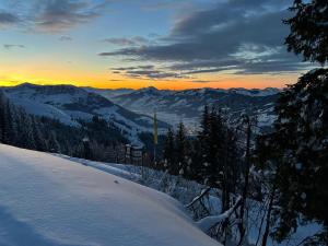 a view of a snowy mountain with the sunset in the background at Hocheckhuette On Top of the Kitzbuehel Hahnenkamm Mountain in Kitzbühel