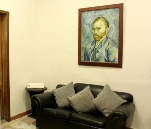 a couch sitting under a painting of a man at RC Apartments in Bogotá