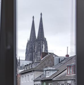 Blick auf eine Kathedrale von einer Stadt mit Dächern in der Unterkunft Apartments Cologne in Köln