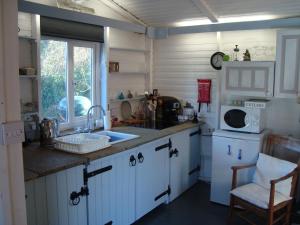 a kitchen with white cabinets and a sink and a microwave at The Barn - Located away from people! in Swanage