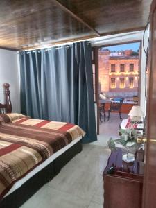 a bedroom with a bed and a window with a table at El Hogar de Carmelita in Guanajuato