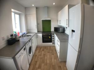 a kitchen with white cabinets and a white refrigerator at The Nook En-suite Room in Plymouth