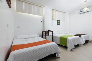 2 camas en una habitación con paredes blancas en Hotel de Alborada, en Guayaquil
