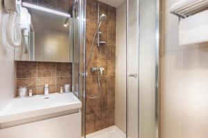 uma casa de banho com um chuveiro e um lavatório. em Hotel Eiffel Segur em Paris