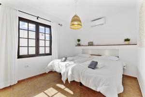 two beds in a room with white walls and a window at Villa 4 - VipVipVillas in Tías +25 photos