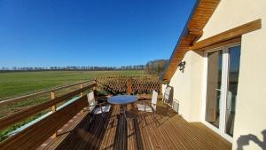 una terraza de madera con mesa y sillas. en L'appel de la foret, en Lyons-la-Forêt