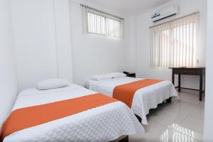 two beds in a room with white and orange at Hotel de Alborada - Cerca Del Aeropuerto in Guayaquil