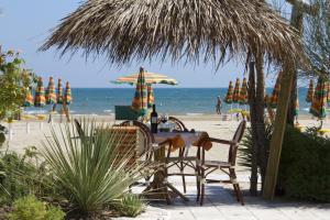 a table and chairs on the beach with umbrellas at Oasi Beach Hotel in Vieste