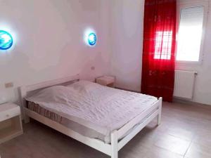 1 dormitorio con cama blanca y cortina roja en Magnifique villa en Centre Ville, en Monastir