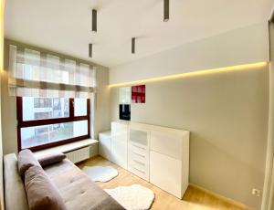 - un salon avec un canapé et une fenêtre dans l'établissement Project Comfort Apartament Przasnyska 7/33 Warszawa, à Varsovie